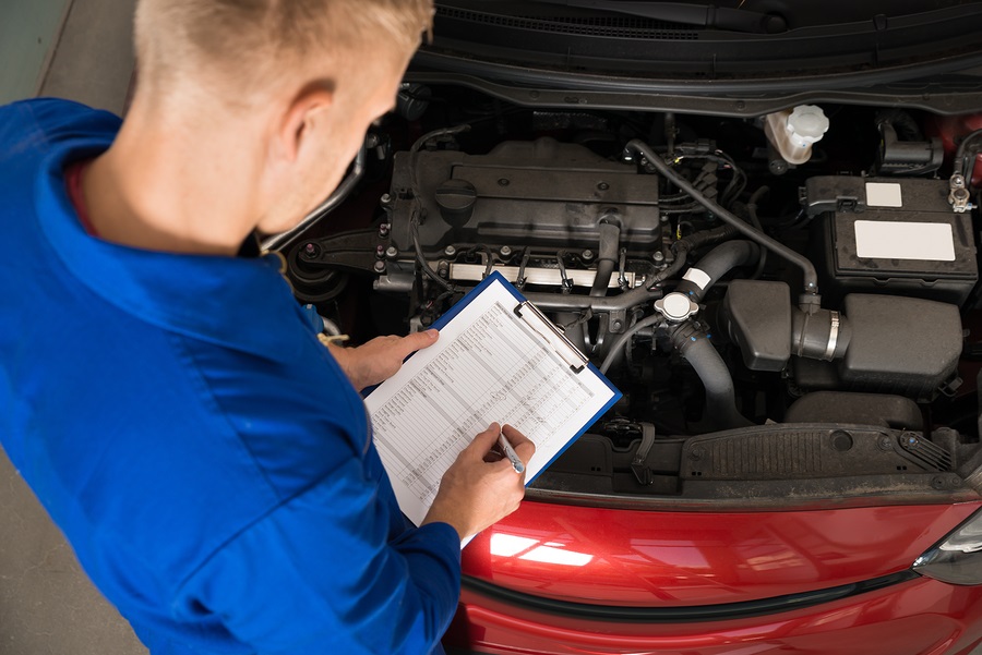 Repair technician inspecting car for diagnostics